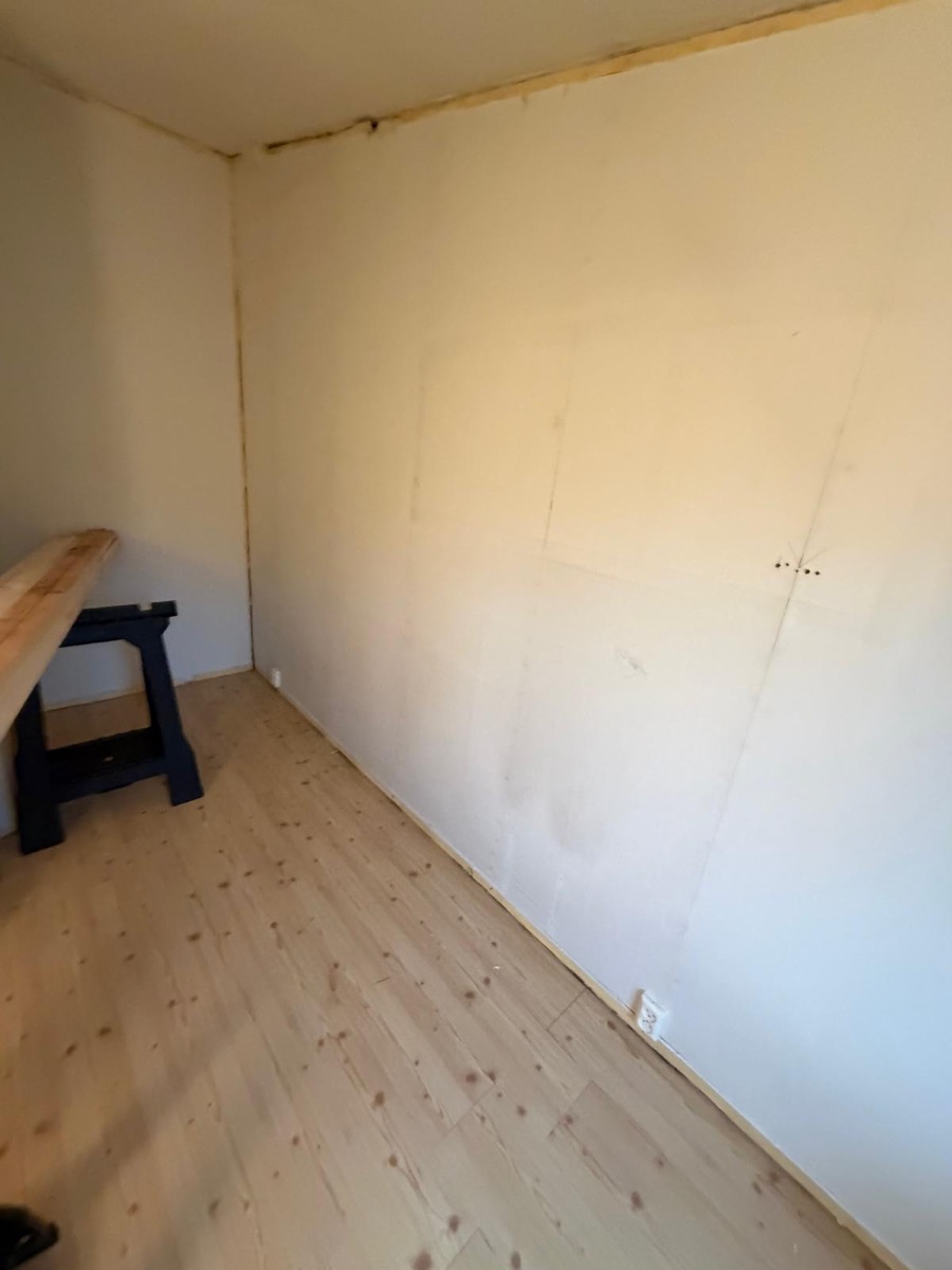 Før: rom med umalt plate på veggen og ubehandlet furugulv